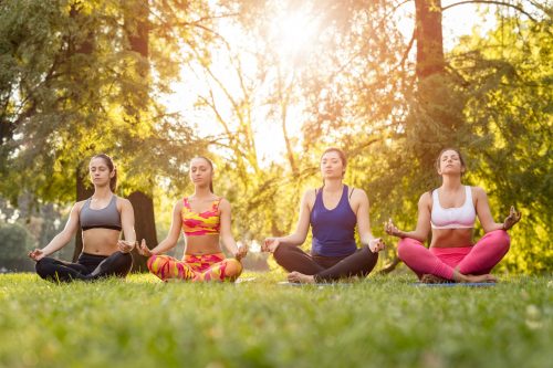 Yoga In The Park Four beautiful female friends meditating in the park.